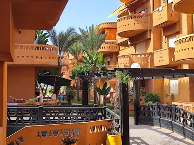 a building with tables and chairs in a courtyard at Appartement high standing piscine jardin mer proche Mohammedia in Figuiq