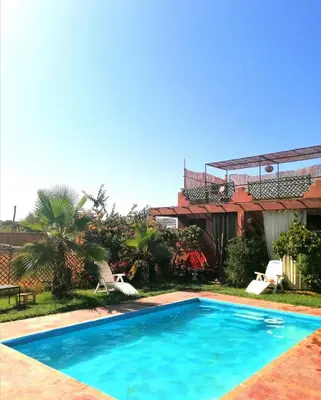 a swimming pool in front of a house at Riad Darga Rouge in Marrakech