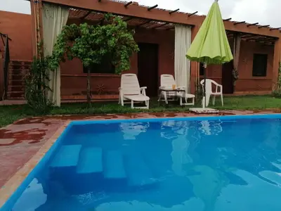 a pool with chairs and a table and a green umbrella at Riad Darga Rouge in Marrakech