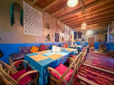 a dining room with blue tables and chairs and a couch at Auberge & Restaurant Agoudal in Agoudal