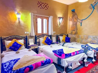 a room with three beds and a painting on the wall at Auberge & Restaurant Agoudal in Agoudal