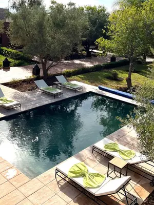 a pool with chaise lounge chairs and a group at LES JARDINS DE MARRAKECH in Marrakech