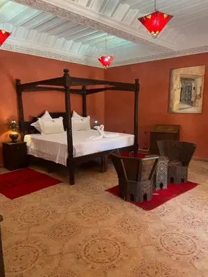a bedroom with a large bed in a room with red walls at LES JARDINS DE MARRAKECH in Marrakech