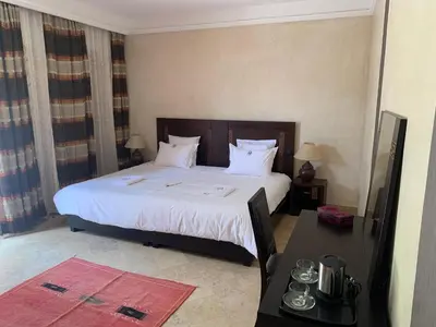 a bedroom with a large bed with white sheets and pillows at LES JARDINS DE MARRAKECH in Marrakech