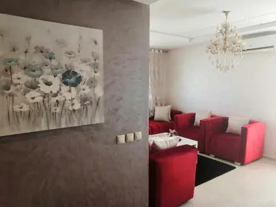 a living room with red furniture and a painting of flowers at Luxury apart in Fes monumental Exclusively for the family in Fès