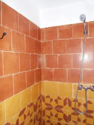 a shower in a bathroom with orange and yellow tiles at Kasbah Agoulzi in Kalaat MGouna