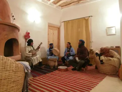 a group of people sitting in a living room with a fireplace at Kasbah Agoulzi in Kalaat MGouna