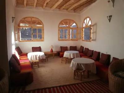 a living room with couches and tables and windows at Kasbah Agoulzi in Kalaat MGouna