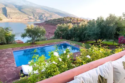 a swimming pool in a garden with a view of a lake at Villa sur le lac Bin el ouidane in Aït Irizane