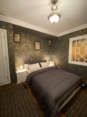 a bedroom with a large bed and a chandelier at Très joli appartement au centre de IFRANE in Ifrane