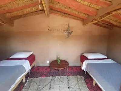 a room with two beds and a table in it at Auberge la Palmeraie in Mhamid