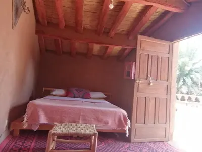 a bedroom with a bed and an open door at Auberge la Palmeraie in Mhamid