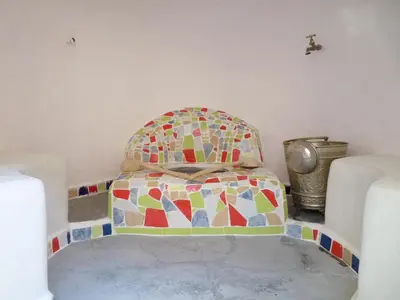 a bed in a room with a mosaic seat at Kasbah Timdaf in Demnat