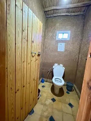 a bathroom with a toilet with wooden stalls at Chegaga Starlight Camp - Mhamid Desert Haven in Mhamid
