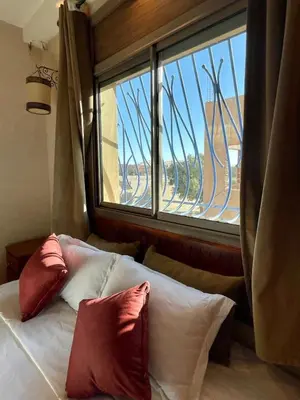 a bed with pillows in a room with a window at Merzouga Hotel Lexpert 