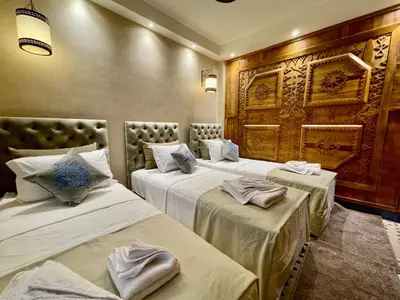 two beds in a hotel room with white sheets at Merzouga Hotel Lexpert 