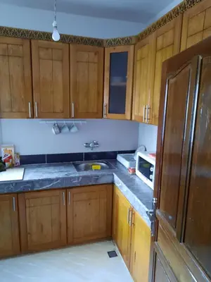 a kitchen with wooden cabinets and a sink and a refrigerator at DARY in Fès