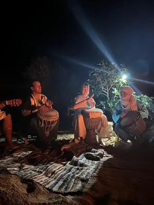 a group of people sitting around a fire at night at Tamaris Camp in Hassilabied