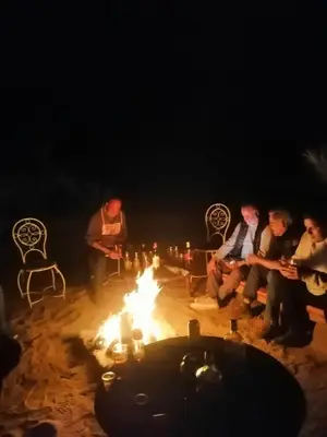 a group of people sitting around a fire at night at Tamaris Camp in Hassilabied