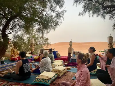 a group of people sitting in the sand in the desert at Tamaris Camp in Hassilabied