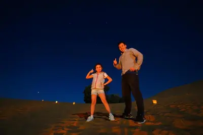 a man and a woman standing on a beach at night at Tamaris Camp in Hassilabied