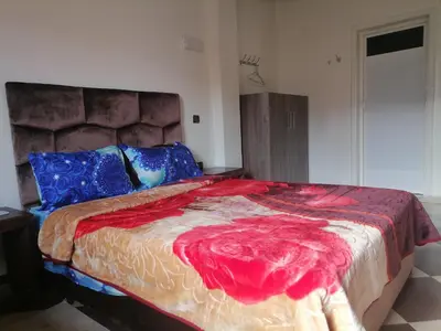 a bedroom with a large bed with a red blanket at ZELLAKA hôtel & café in Khouribga