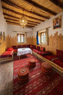 a living room with red furniture and a table at Casa Mona in Merzouga