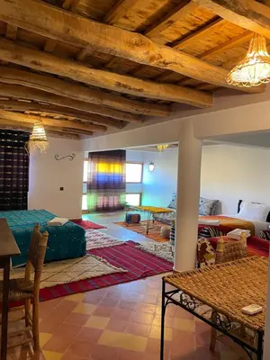 a living room with a bed and a table at Maison D'hôte La Vallée Des Figues in Tamellalt