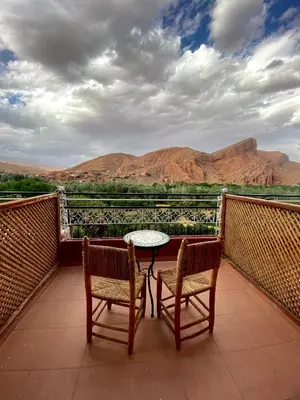 a table and two chairs on a balcony with mountains at Maison D'hôte La Vallée Des Figues in Tamellalt