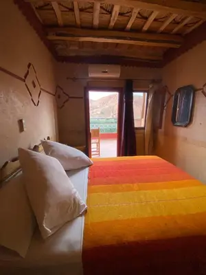 a bedroom with a colorful bed with a window at Maison D'hôte La Vallée Des Figues in Tamellalt