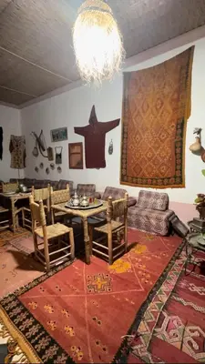 a living room with a table and chairs and a chandelier at La Kasbah du Jardin in Aït Ben Haddou