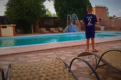 a young boy standing on a board by a swimming pool at La Kasbah du Jardin in Aït Ben Haddou