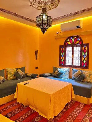 a bedroom with a bed and a couch with a window at Dromadaire Gourmand in Zagora