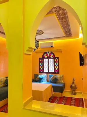 a yellow room with a bed and a window at Dromadaire Gourmand in Zagora