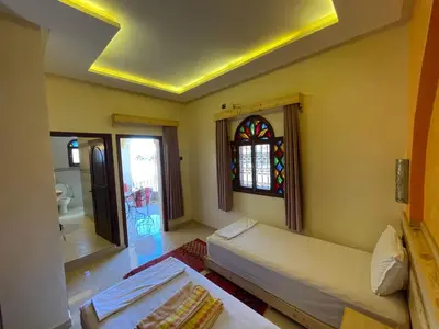 a room with two beds and a stained glass window at Dromadaire Gourmand in Zagora