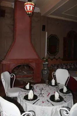 a dining room with a table and a fireplace at Dromadaire Gourmand in Zagora