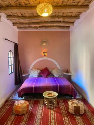 a bedroom with a purple bed and a table at Auberge Tissadrine in Akhendachou nʼAït Ouffi