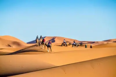 a group of people riding horses in the desert at Night Luxury Dunes Camp in Merzouga