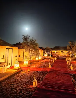 a group of tables and lights in a compound at night at Night Luxury Dunes Camp in Merzouga