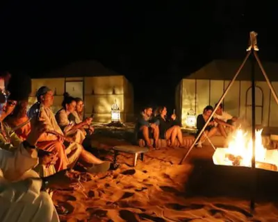 a group of people sitting around a fire at Night Luxury Dunes Camp in Merzouga