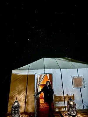 a man standing inside of a tent at night at Night Luxury Dunes Camp in Merzouga