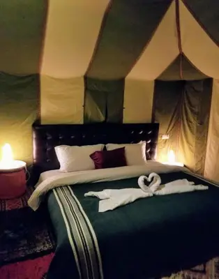 a bedroom with a bed with two swans on it at Night Luxury Dunes Camp in Merzouga