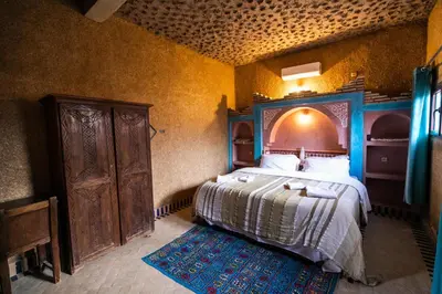 a bedroom with a bed with a wooden headboard and a rug at Ksar Bicha in Merzouga