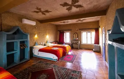 a bedroom with two beds and a fireplace at Ksar Bicha in Merzouga