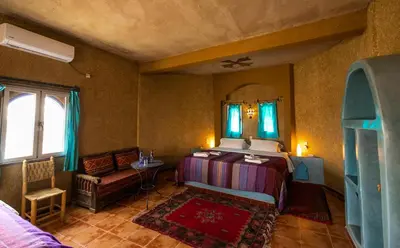 a bedroom with a bed and a table and a mirror at Ksar Bicha in Merzouga