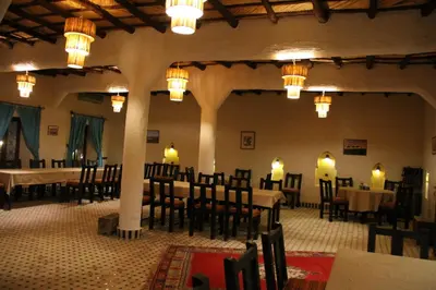 a dining room with tables and chairs and chandeliers at Ksar Bicha in Merzouga