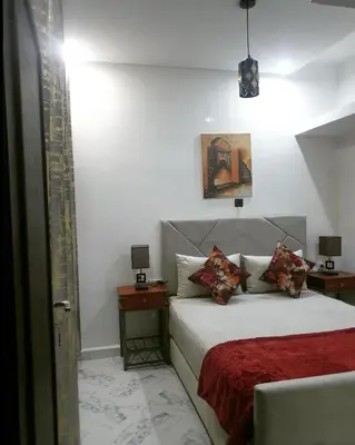 a bedroom with a bed with a red blanket and two tables at White House in Azrou