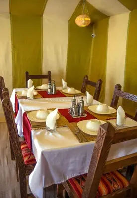 a dining room with a table with plates and napkins at Desert Romantic Camp in Merzouga