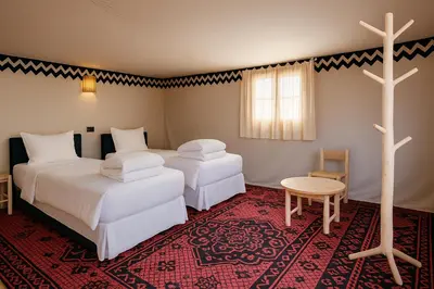 two beds in a room with a cross on the floor at Ame camp in Merzouga