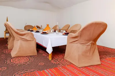 a dining room with a table and chairs at Ame camp in Merzouga